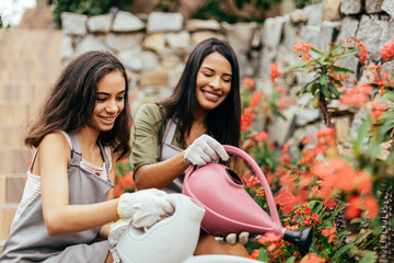 Latin mother and daughter taking care of plants at home