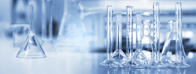 Wall Mural - glass flask and cylinder in soft blue light medical science laboratory banner background
