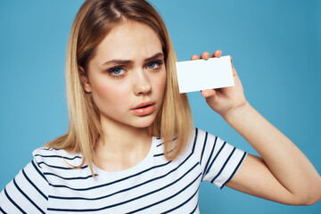 Poster - Woman with a business card in her hands a striped T-shirt blue background Copy Space