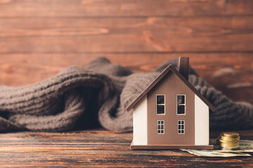 Figure of house, money and warm scarf on table. Concept of heating season