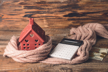 Figure of house, calculator, money and warm scarf on table. Concept of heating season