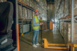 © zinkevych - Worker in a vest and helmet standing in the warehouse in the aisle