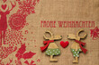 FROHE WEIHNACHTEN 2 Rentiere aus Holz mit rotem Herz auf Hintergrund aus Jute marodem Schriftzug und skandinavischen traditionellen Ornamenten