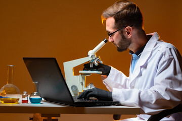 Poster - scientist looks through microscope. young man works in a laboratory. scientist uses an electron micr