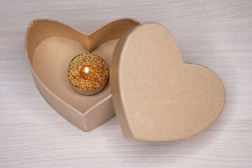 Canvas Print - Closeup shot of a candle with golden glitter in a heart-shaped box