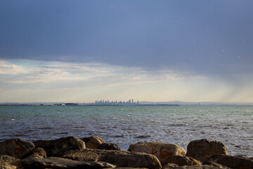 skyline of melbourne viewed over the sea from rocks