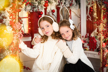 two red-haired sisters on the veranda of a house decorated for Christmas. garland lights, bokeh