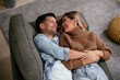 © JustLife - Young loving couple relaxing on sofa together. Happy couple enjoying at home.