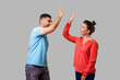 © khosrork - Side view portrait of excited amazed young couple in casual wear standing saying hello and giving high five, friends greeting each other, glad to meet. isolated on gray background, indoor studio shot