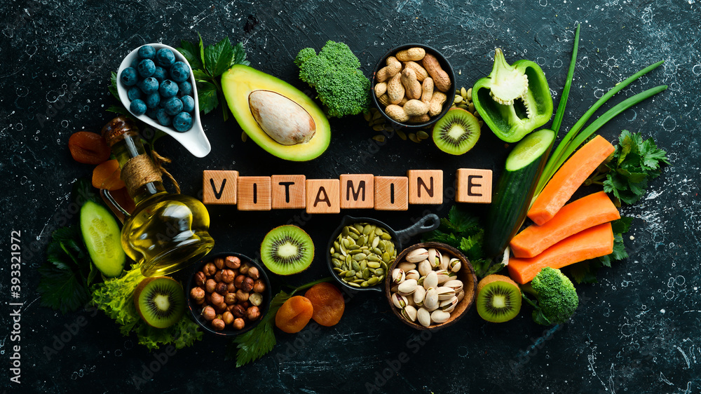 Foods rich in vitamin E: pumpkin, broccoli, dried apricots, parsley, avocado and vegetables. The inscription "Vitamin E". Top view. - obrazy, fototapety, plakaty 