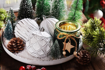 Wall Mural - Christmas decoration with white ornaments and candle in green glass jar on round tray