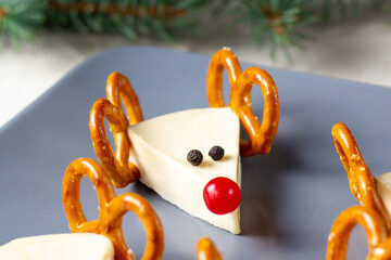 Wall Mural - Funny christmas snack in a shapes of deer for kids party. Concept New year food from cheese and pretzels