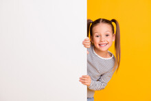 Photo Of Young Happy Smiling Little Girl Child Kid Stand Behind White Wall Isolated On Yellow Color Background