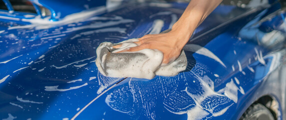 car detailing, close up hand holding a sponge and cleaning the car