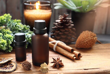 Natural Essential Oil Bottles Are On The Wooden Table With Cinnamon Sticks, Star Anise, Pinecone And Potpourri With Background Of Scented Candles And Wooden Wall Decorate In The Living Room