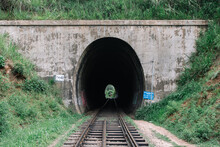 View Of Train Tracks Leading To In A Concrete Tunnel Bridge With View Through Thru To The Other Side Surrounded By Greenery Grass Mounds And Hill During Summer In Sri Lanka