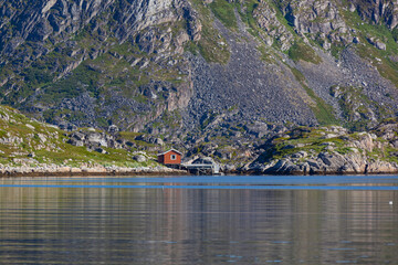 Wall Mural - Red wooden shed at a mountain foot on the shore of Barents sea in the Northern Norway, Finnmark