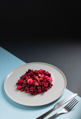 Wall Mural - Vinaigrette salad of beetroot, potatoes, beans and carrots served on a white plate on a black and blue background. Natural vegetarian detox snack. Traditional Russian and Ukrainian cuisine