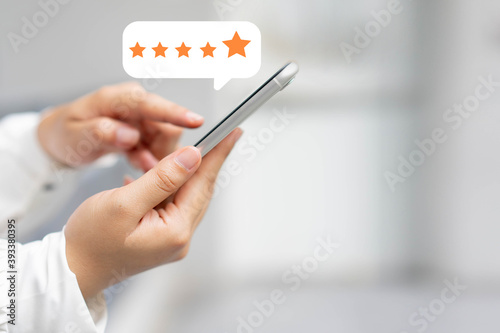 close up on customer woman hand pressing on smartphone screen with gold five star rating feedback icon and press level three rank (good) for give score point to review the service business concept