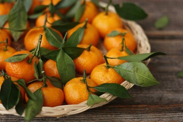 Sticker - Juicy tangerines with green leaves on a wooden table 