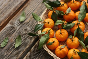 Sticker - Juicy tangerines with green leaves on a wooden table 