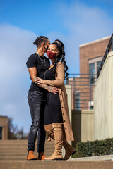 Wall Mural - African American lesbian couple wearing black clothes and face masks to protect from Covid-19 Coronavirus pandemic