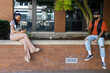 © Mat Hayward - Two African American women wearing masks to protect from the Covid-19 coronavirus sit 6 feet apart for social distancing while looking at their smartphones outside