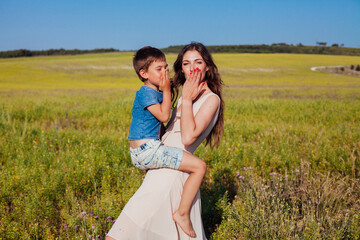 Beautiful woman mom hugs young son in nature on a walk