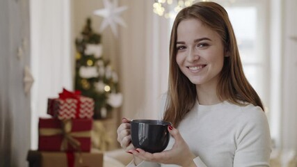 Poster - Happy young woman indoors at home at Christmas, holding cup of coffee.