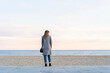 © VITTA GALLERY/Westend61 - Young woman looking at sea while standing on promenade at beach enjoying sunset