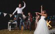 © David Pereiras/Westend61 - Surprised bride looking at man jumping on a night field party with friends