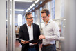 © Daniel Ingold/Westend61 - Two businessmen in factory looking at folder
