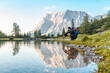 © Daniel Ingold/Westend61 - Austria, Tyrol, Hiker taking a break, crouching by the lake