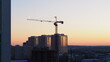 © Azovsky - Building a house at sunset. Crane, silhouettes of workers.