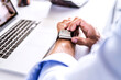 © HalfPoint/Westend61 - Close-up of businessman at desk with laptop using smartwatch