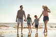 Happy family walking on sandy beach near sea