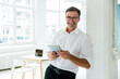 © Sebastian Moelleken/Westend61 - Portrait of happy businessman with tablet in bright office
