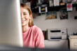 © Moll/Schoepgens Fotodesign GbR/Westend61 - Portrait of smiling young woman behind computer screen at desk at home