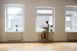 © Sebastian Moelleken/Westend61 - Mature woman in empty room holding laptop at the window