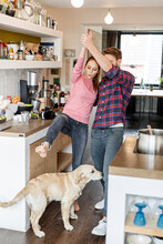 Young Couple With Dog Dancing In The Kitchen