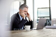© Rainer Berg/Westend61 - Businessman with headaches sitting at desk in office
