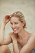 © philipp nemenz/Westend61 - Portrait of laughing blond woman sitting on the beach