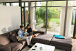 © steve brookland/Westend61 - Parents and son sitting on sofa in modern living room using laptop at home