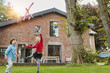 © Roger Richter/Westend61 - Two children playing with toy airplane in garden of their home