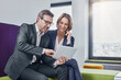 © Roger Richter/Westend61 - Smiling businessman and businesswoman using tablet in office lounge together