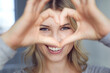 © philipp nemenz/Westend61 - Portrait of laughing woman building heart with her fingers