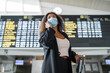 © SERGIO NIEVAS/Westend61 - Woman wearing protective face mask talking on smart phone at airport