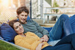 © Roger Richter/Westend61 - Smiling couple lying in hammock in garden of their home