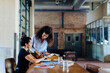© Sofie Delauw/Westend61 - Two young businesswomen talking at conference table in loft office