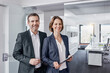 © Roger Richter/Westend61 - Portrait of smiling businessman and businesswoman with tablet in office